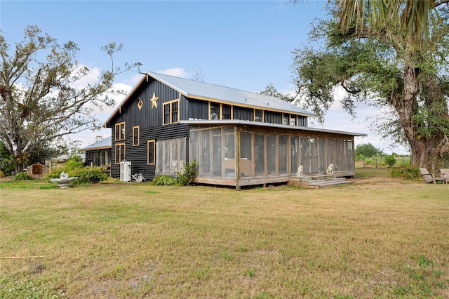 rear view of house with a lawn and a sunroom