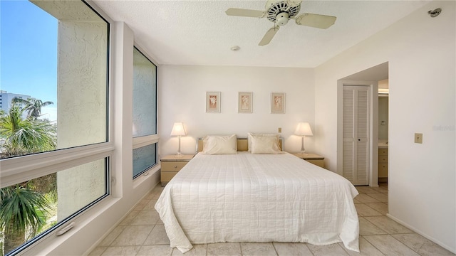 bedroom with ceiling fan, light tile patterned flooring, a textured ceiling, and a closet