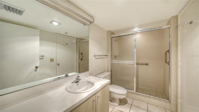 bathroom with toilet, vanity, tile patterned floors, and a shower with shower door