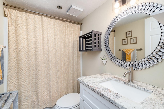 bathroom with vanity, toilet, and a textured ceiling