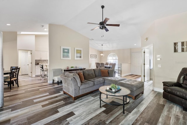 living room featuring ceiling fan, wood-type flooring, and lofted ceiling