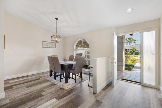 dining area featuring hardwood / wood-style floors, an inviting chandelier, and lofted ceiling