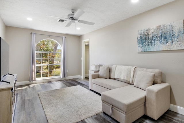 living room featuring ceiling fan and dark wood-type flooring