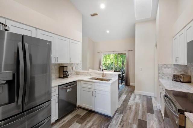 kitchen featuring kitchen peninsula, appliances with stainless steel finishes, backsplash, sink, and white cabinets