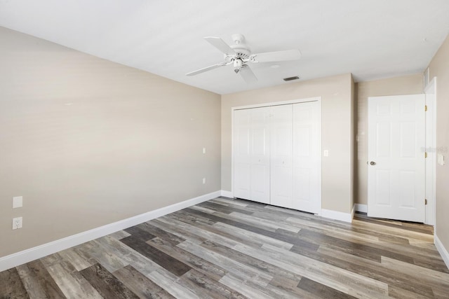 unfurnished bedroom with ceiling fan, a closet, and hardwood / wood-style floors