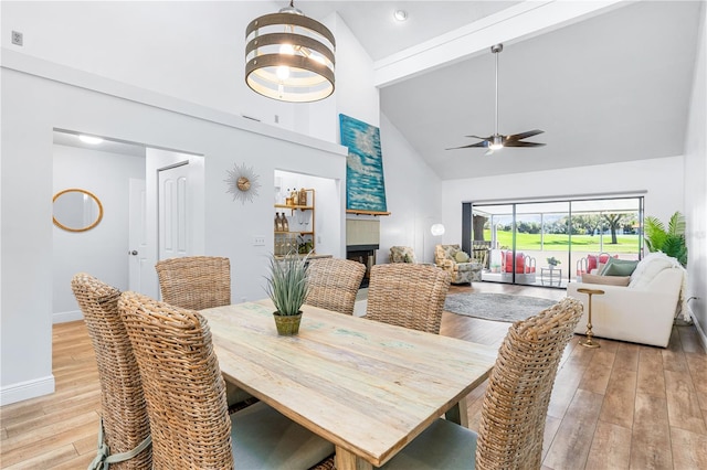 dining space featuring light hardwood / wood-style floors, high vaulted ceiling, and ceiling fan