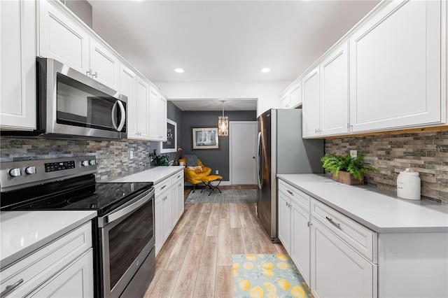 kitchen featuring white cabinets, light hardwood / wood-style floors, stainless steel appliances, and hanging light fixtures