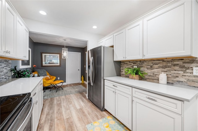 kitchen featuring backsplash, white cabinetry, stainless steel appliances, and light wood-type flooring