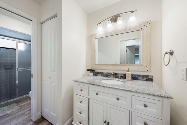 bathroom with toilet, vanity, a shower with shower door, and hardwood / wood-style flooring