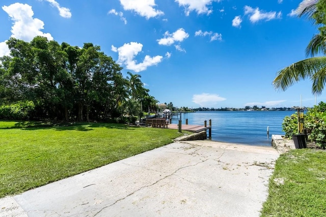 view of dock featuring a lawn and a water view