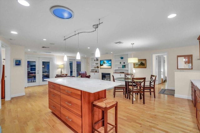 kitchen with french doors, a kitchen island, pendant lighting, and light hardwood / wood-style flooring