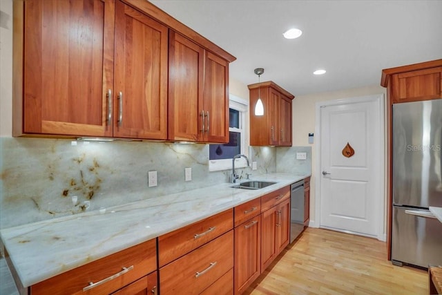 kitchen with light stone countertops, appliances with stainless steel finishes, backsplash, sink, and pendant lighting