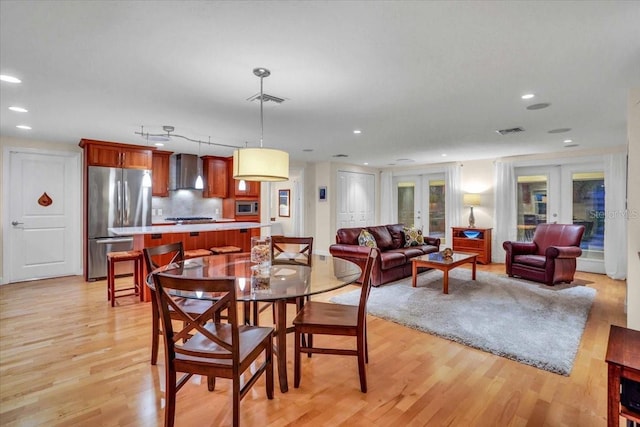 dining room with light hardwood / wood-style floors and french doors