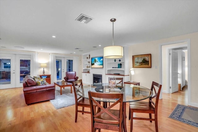 dining room with built in shelves, french doors, and light hardwood / wood-style flooring