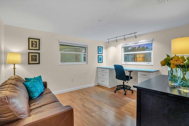 office space with light hardwood / wood-style flooring and track lighting