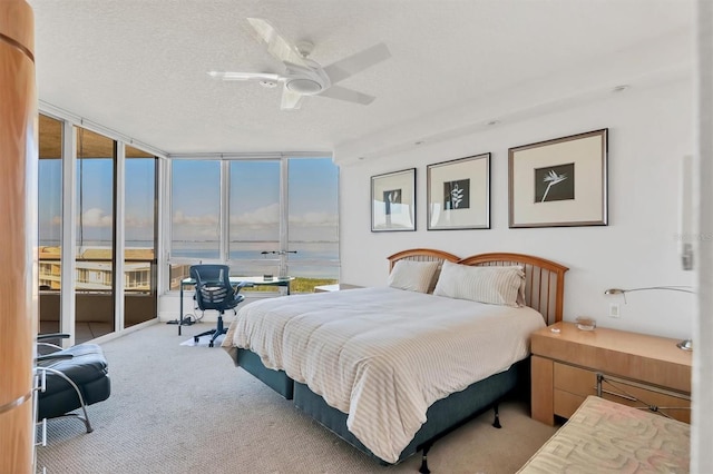 bedroom featuring access to exterior, ceiling fan, expansive windows, and a water view