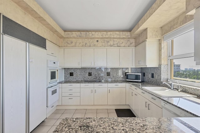 kitchen with white appliances, sink, decorative backsplash, light tile patterned flooring, and light stone counters