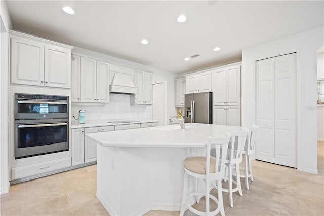 kitchen with white cabinets, sink, appliances with stainless steel finishes, and an island with sink