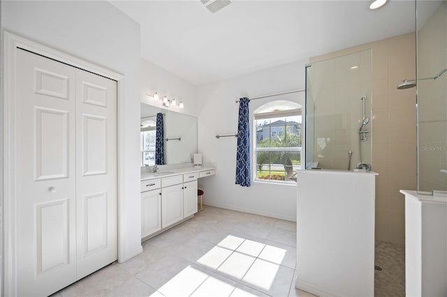 bathroom featuring tile patterned flooring, plenty of natural light, tiled shower, and vanity