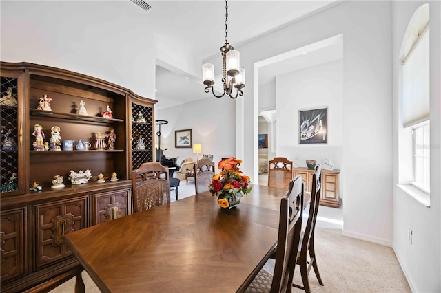 dining room with light carpet and a chandelier