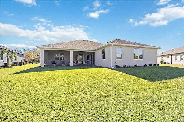 rear view of house featuring a lawn and a sunroom