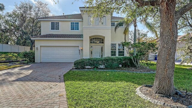 mediterranean / spanish house featuring a garage and a front lawn