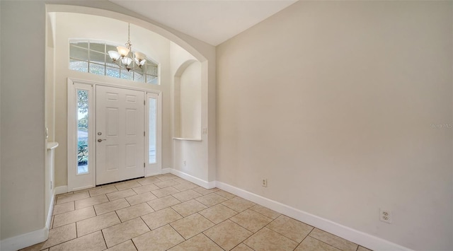 tiled foyer entrance featuring an inviting chandelier, a wealth of natural light, and lofted ceiling