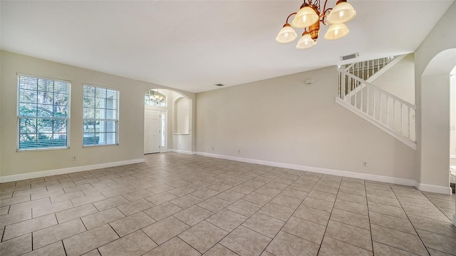 spare room featuring light tile patterned floors and an inviting chandelier