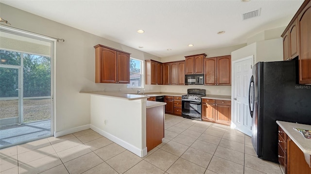 kitchen with a healthy amount of sunlight, light tile patterned flooring, and black appliances