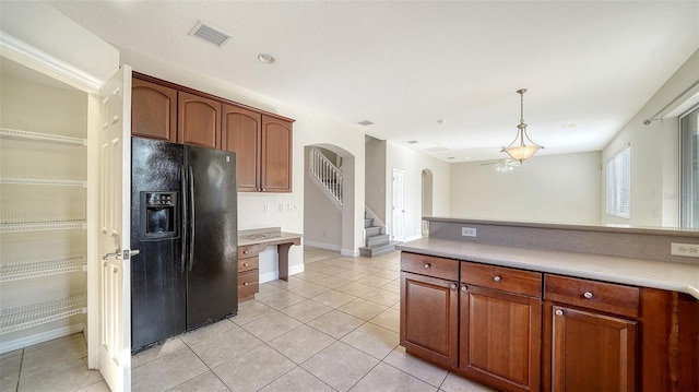 kitchen with light tile patterned floors, black refrigerator with ice dispenser, and hanging light fixtures