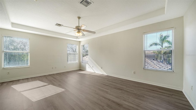 unfurnished room featuring dark hardwood / wood-style flooring, a raised ceiling, and ceiling fan