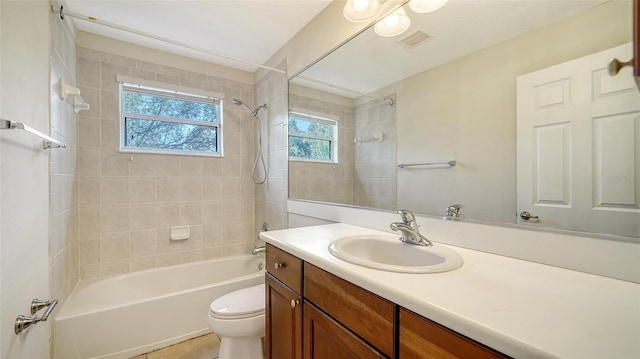 full bathroom with vanity, tiled shower / bath combo, toilet, and plenty of natural light