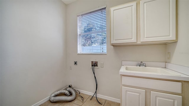 clothes washing area with cabinets, sink, washer hookup, light tile patterned floors, and hookup for an electric dryer