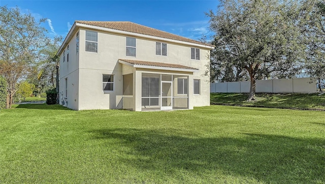 rear view of property with a sunroom and a lawn