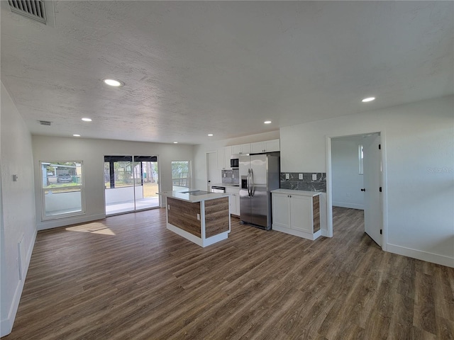 kitchen with stainless steel refrigerator with ice dispenser, a kitchen island, stovetop, dark hardwood / wood-style flooring, and white cabinetry