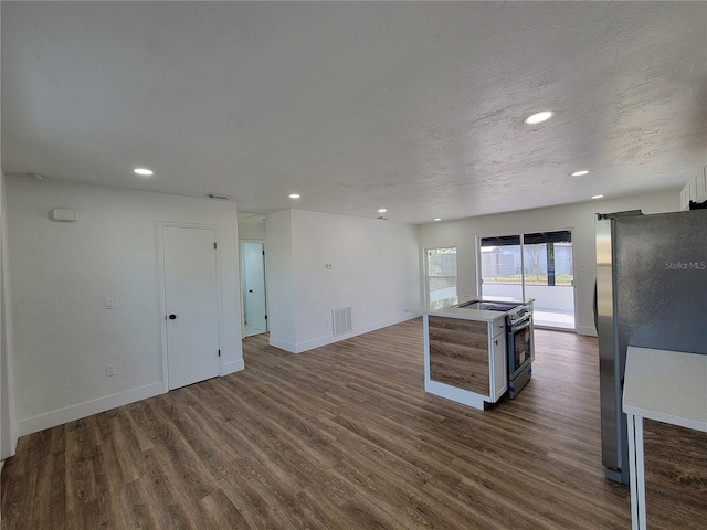 kitchen with stainless steel appliances, a kitchen island, and dark wood-type flooring