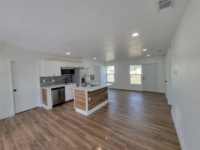 kitchen featuring white cabinetry, a center island, dark hardwood / wood-style flooring, decorative backsplash, and appliances with stainless steel finishes