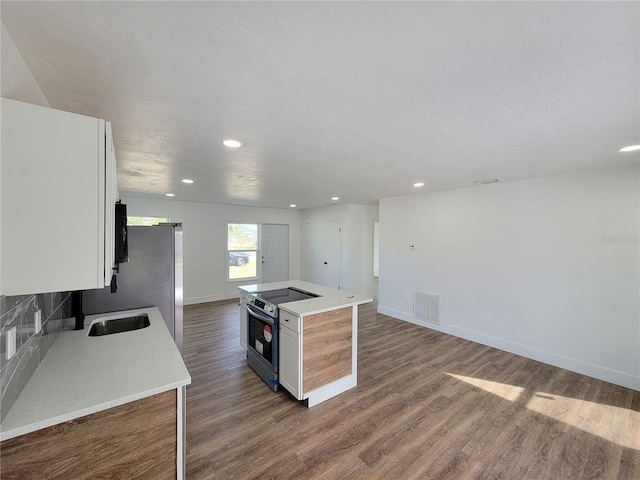 kitchen featuring stainless steel electric range oven, a kitchen island, dark wood-type flooring, sink, and white cabinetry