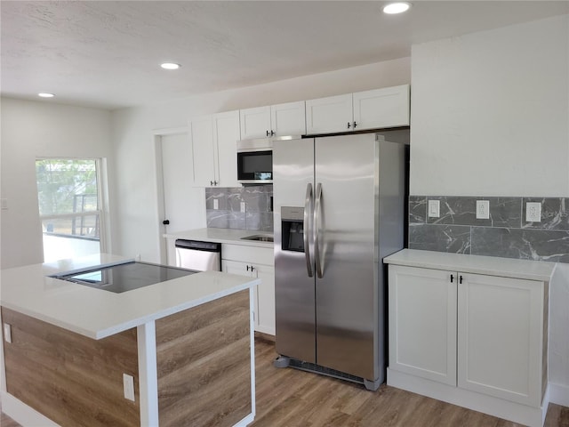 kitchen featuring a center island, white cabinets, light hardwood / wood-style flooring, tasteful backsplash, and stainless steel appliances