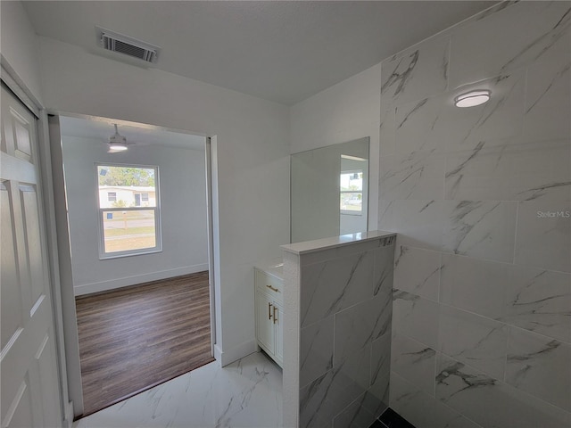 bathroom with ceiling fan, hardwood / wood-style floors, vanity, and tiled shower