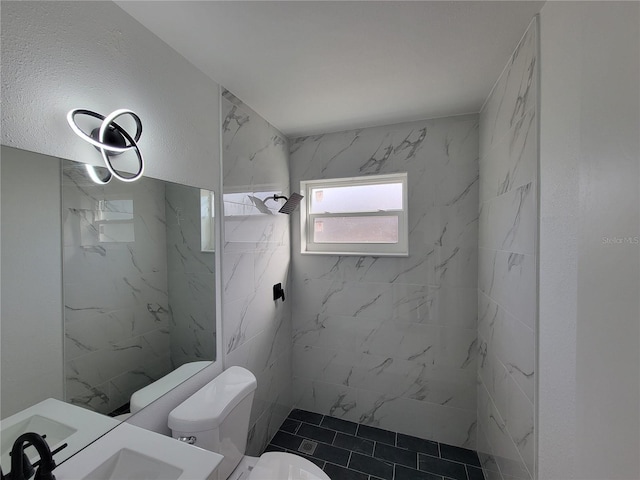 bathroom with toilet, vanity, and tiled shower