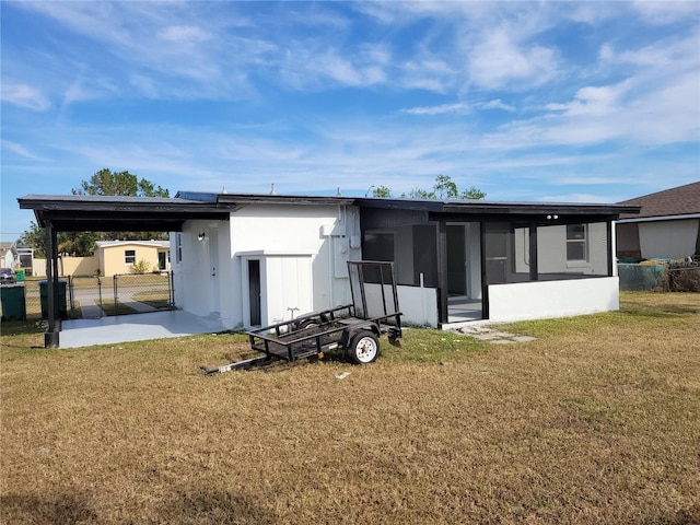 rear view of property with a carport, a sunroom, and a lawn