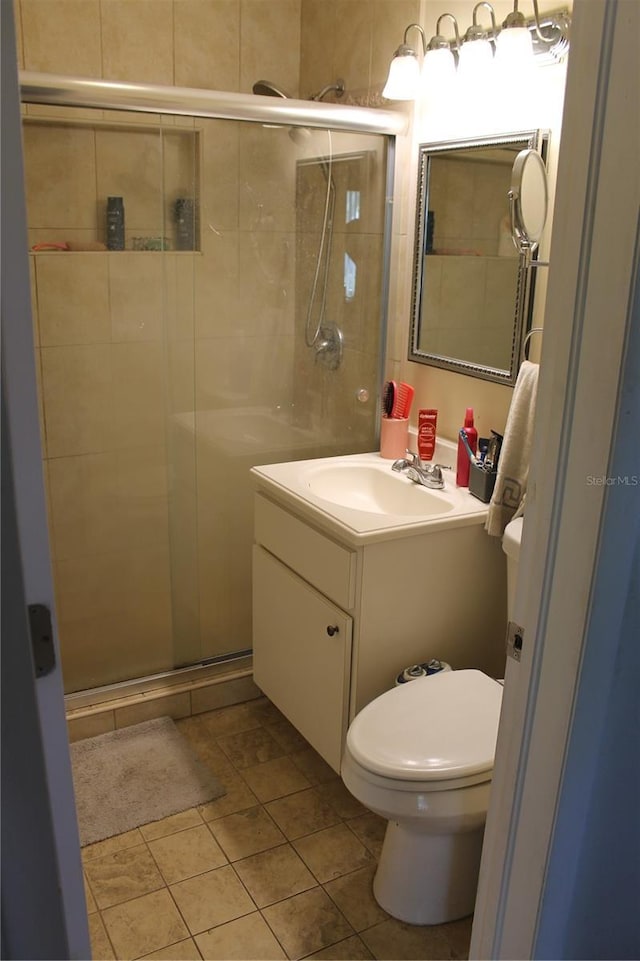 bathroom with tile patterned flooring, vanity, toilet, and a shower with door