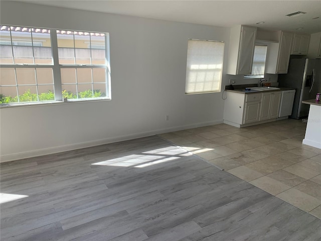 kitchen with stainless steel fridge with ice dispenser, white cabinetry, and sink