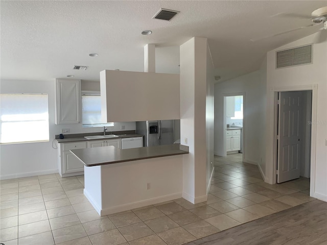 kitchen with lofted ceiling, sink, white cabinetry, light tile patterned flooring, and stainless steel fridge with ice dispenser