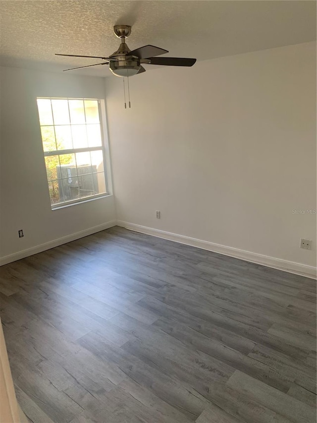 spare room with a textured ceiling, ceiling fan, and dark wood-type flooring