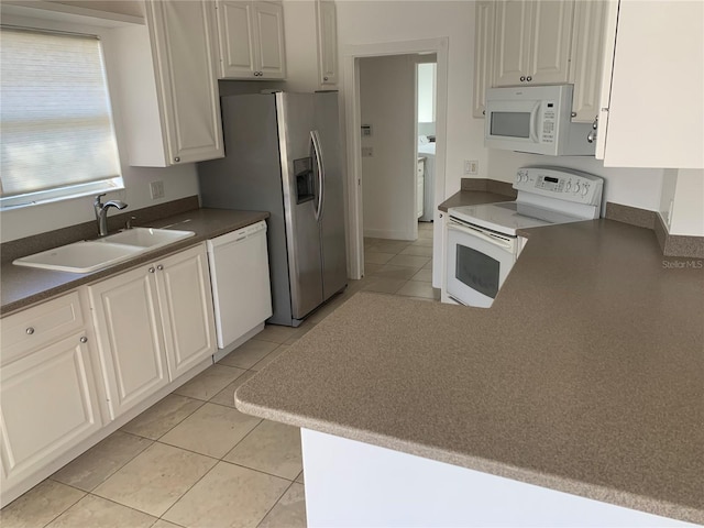 kitchen with kitchen peninsula, white appliances, sink, light tile patterned floors, and white cabinets