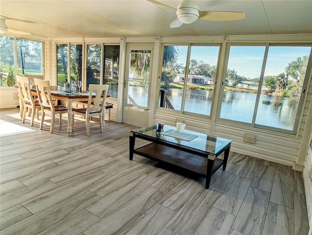 sunroom featuring a water view and ceiling fan