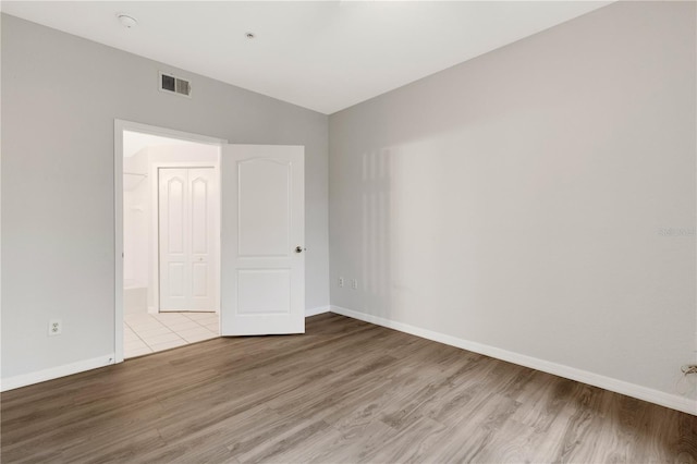 unfurnished bedroom with ensuite bathroom and light hardwood / wood-style flooring