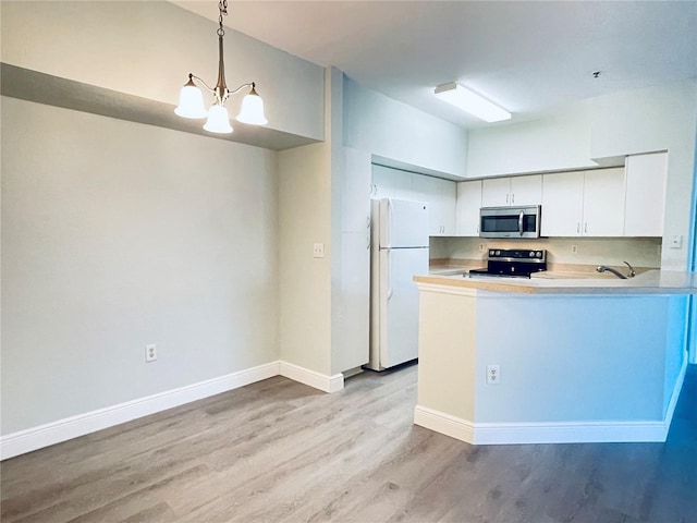 kitchen featuring pendant lighting, white cabinetry, white fridge, kitchen peninsula, and electric stove